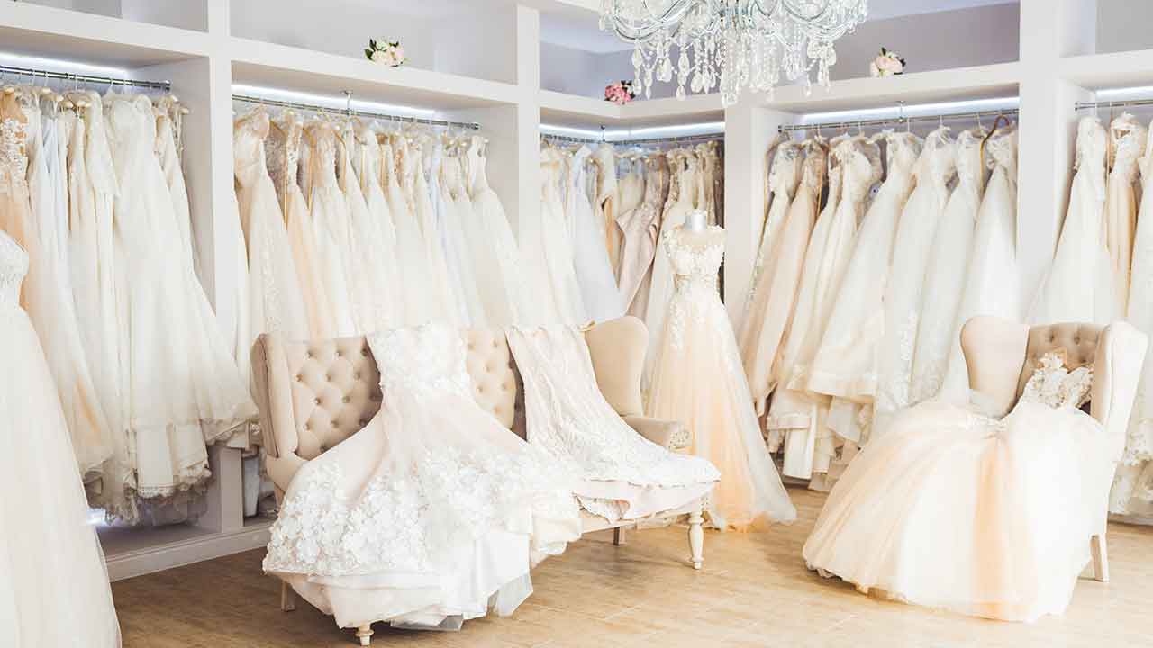 A room full of wedding dresses and a chandelier.