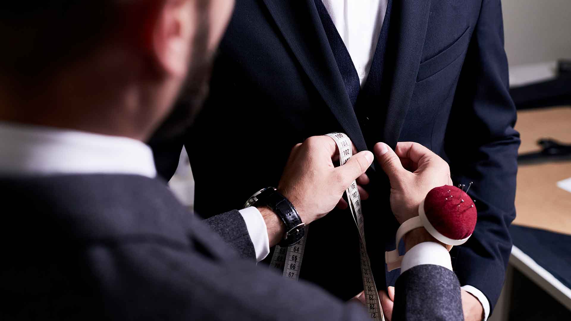 A man in a suit is putting on a tie.