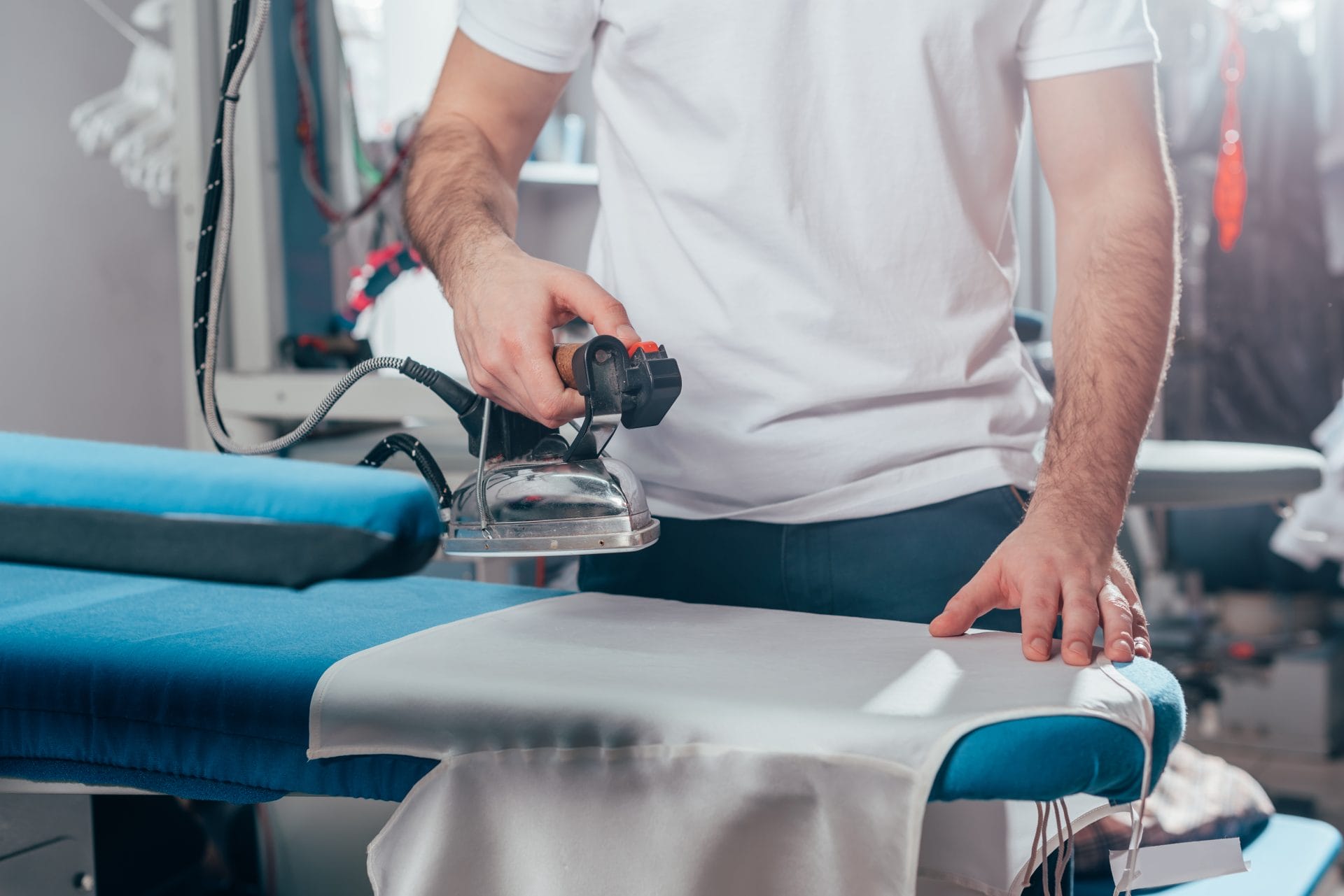 A man ironing clothes in a laundry room.